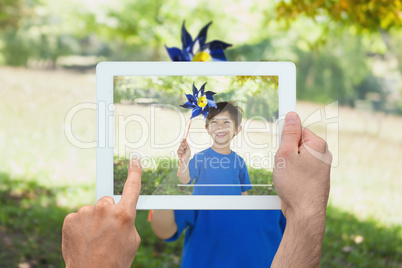 Composite image of hand holding tablet pc