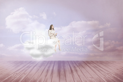 Composite image of businesswoman holding tablet and looking up