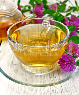 Tea with clover in glass cup on light board