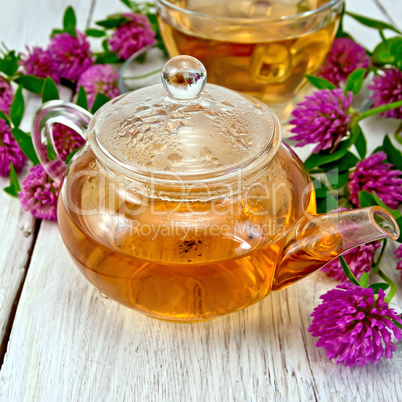 Tea with clover in glass teapot on board
