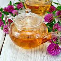 Tea with clover in glass teapot on board
