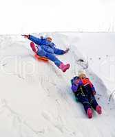 Two girls on sled through the snow to slide
