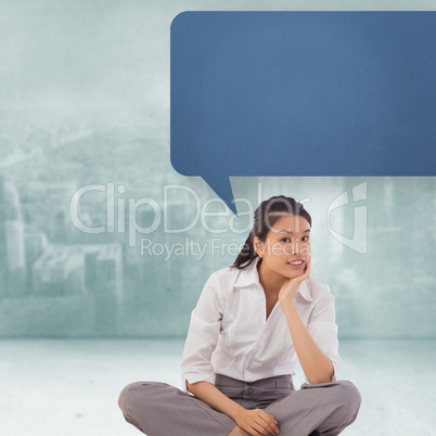 Composite image of businesswoman sitting cross legged with speec