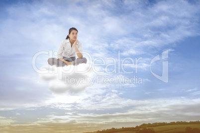 Composite image of businesswoman sitting cross legged thinking