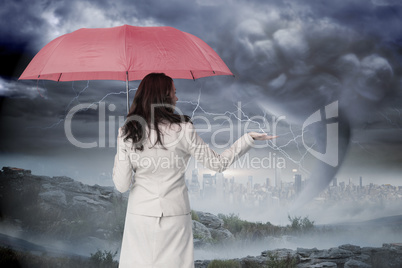 Composite image of businesswoman holding umbrella