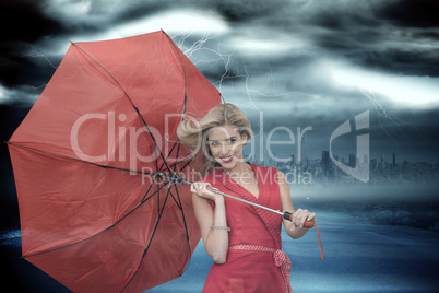 Composite image of smiling blonde holding umbrella