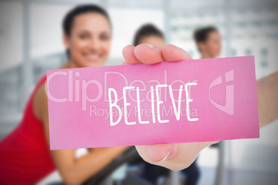 Woman holding pink card saying believe