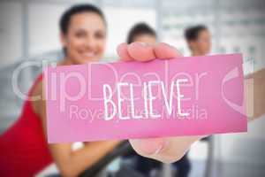 Woman holding pink card saying believe