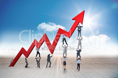 Composite image of business team holding up arrow