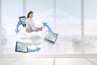 Composite image of businesswoman sitting in lotus pose