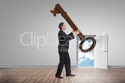 Composite image of stressed businessman carrying large key