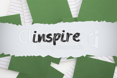 Inspire against green paper strewn over notepad