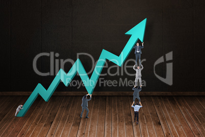 Composite image of business team holding up arrow