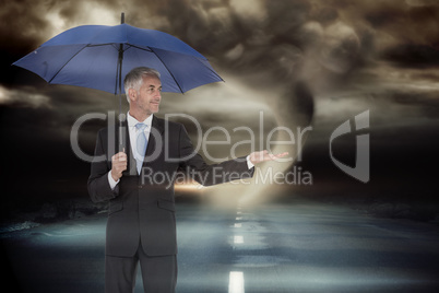 Composite image of happy businessman holding umbrella