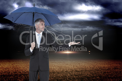 Composite image of happy businessman holding umbrella