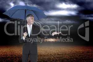 Composite image of happy businessman holding umbrella