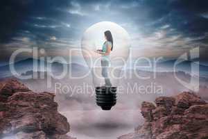 Composite image of woman holding laptop in light bulb