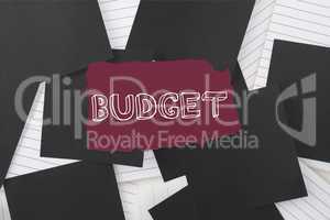 Budget against black paper strewn over notepad