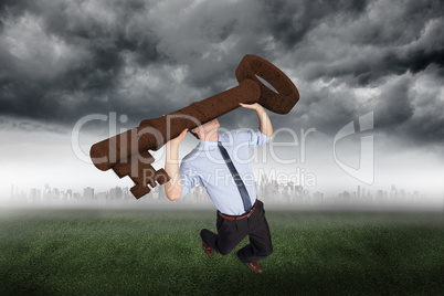 Composite image of businessman carrying large key