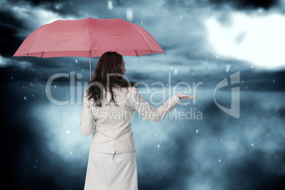 Composite image of businesswoman holding umbrella