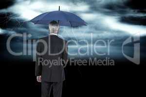 Composite image of businessman holding umbrella