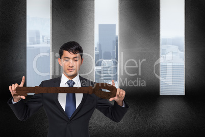 Composite image of unsmiling businessman carrying large key