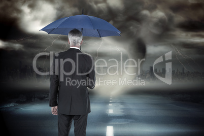 Composite image of businessman holding umbrella