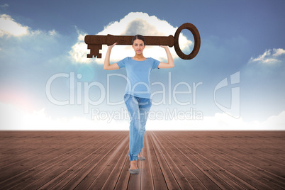 Composite image of annoyed brunette carrying large key