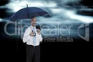 Composite image of happy businessman holding umbrella