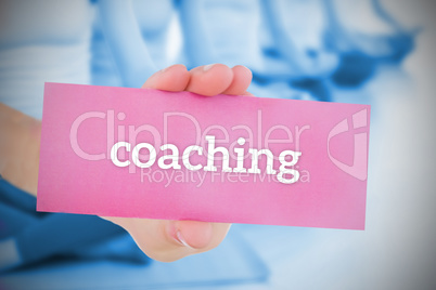 Woman holding pink card saying coaching