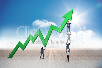 Composite image of business team holding up arrow