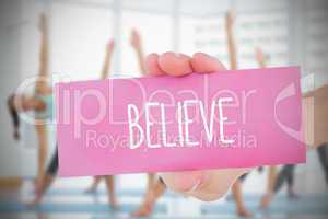 Woman holding pink card saying believe