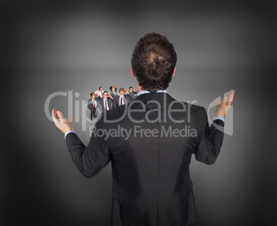 Composite image of gesturing businessman with tiny businessmen