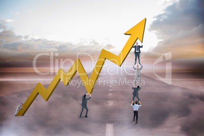 Composite image of business team holding up arrow