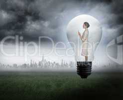 Composite image of thinking businesswoman in light bulb