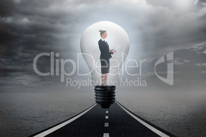 Composite image of businesswoman holding tablet in light bulb