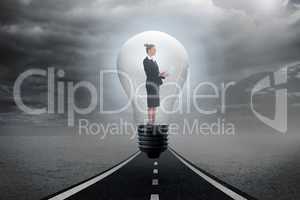 Composite image of businesswoman holding tablet in light bulb