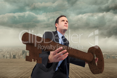 Composite image of businessman carrying large key