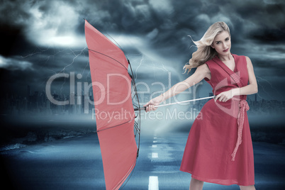 Composite image of elegant blonde holding umbrella