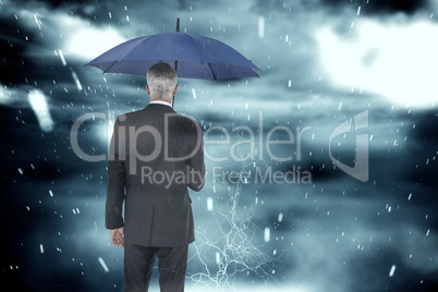 Composite image of businessman holding umbrella