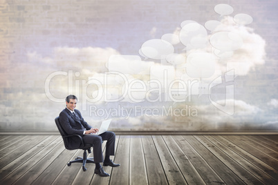 Composite image of young businessman sitting working with a lapt