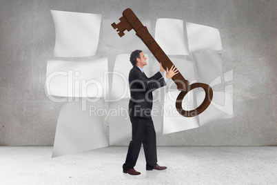 Composite image of stressed businessman carrying large key