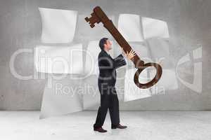 Composite image of stressed businessman carrying large key