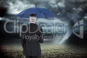 Composite image of businessman holding umbrella