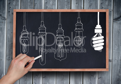 Composite image of hand drawing light bulbs with chalk