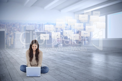 Composite image of brunette sitting on floor using laptop