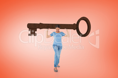 Composite image of annoyed brunette carrying large key