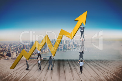 Composite image of business team holding up arrow