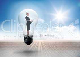 Composite image of businesswoman holding tablet in light bulb