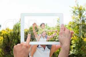 Composite image of hand holding tablet pc